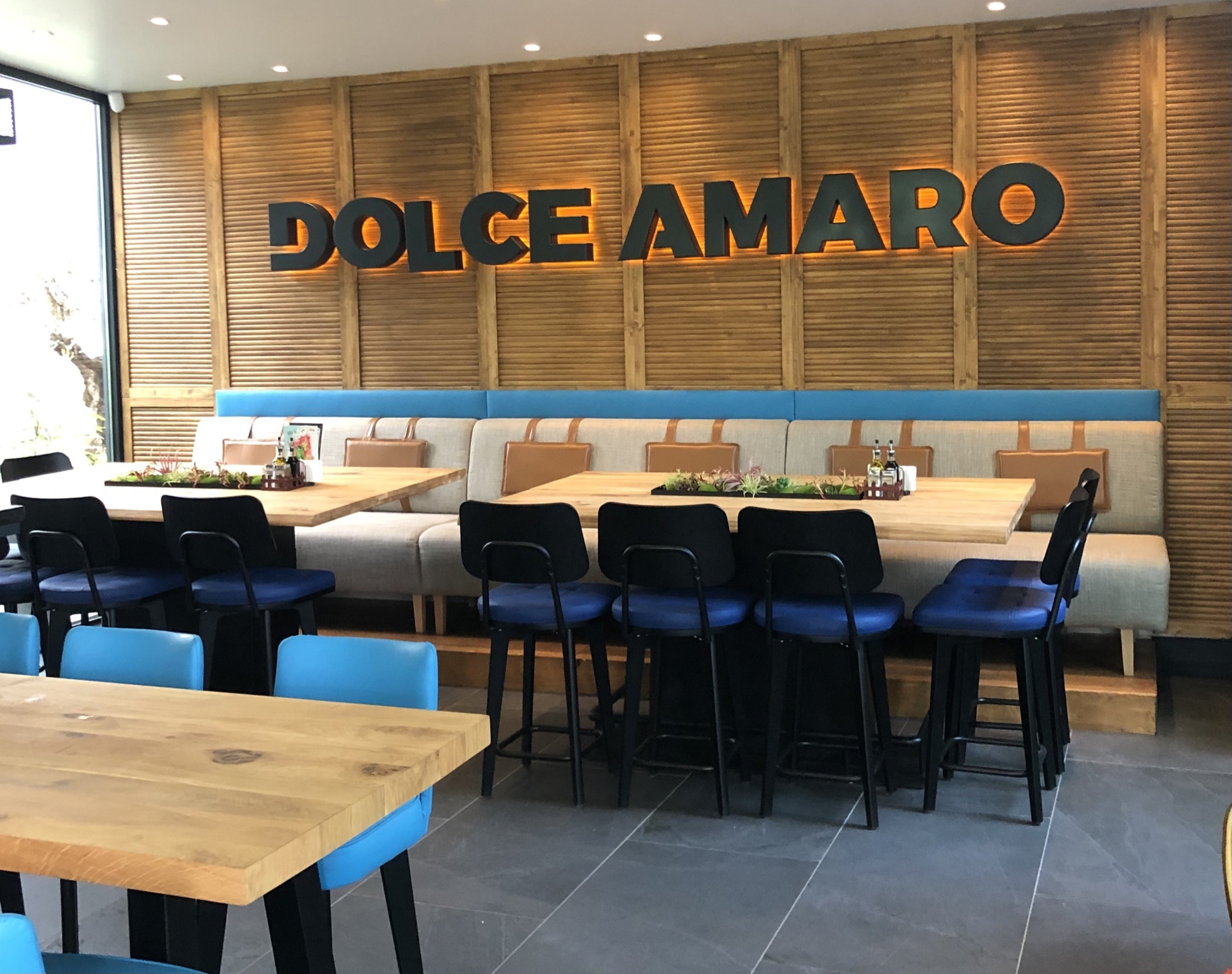 Стена с дървена облицовка, надпис Dolce Amaro и мека мебел